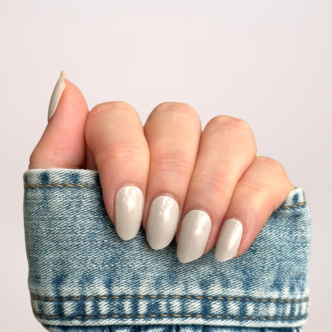 Close-up van een hand met gellakstickers in de kleur Frosted Cream, een zachte gebroken wit/lichtgrijze tint, die een elegante en frisse look geeft
