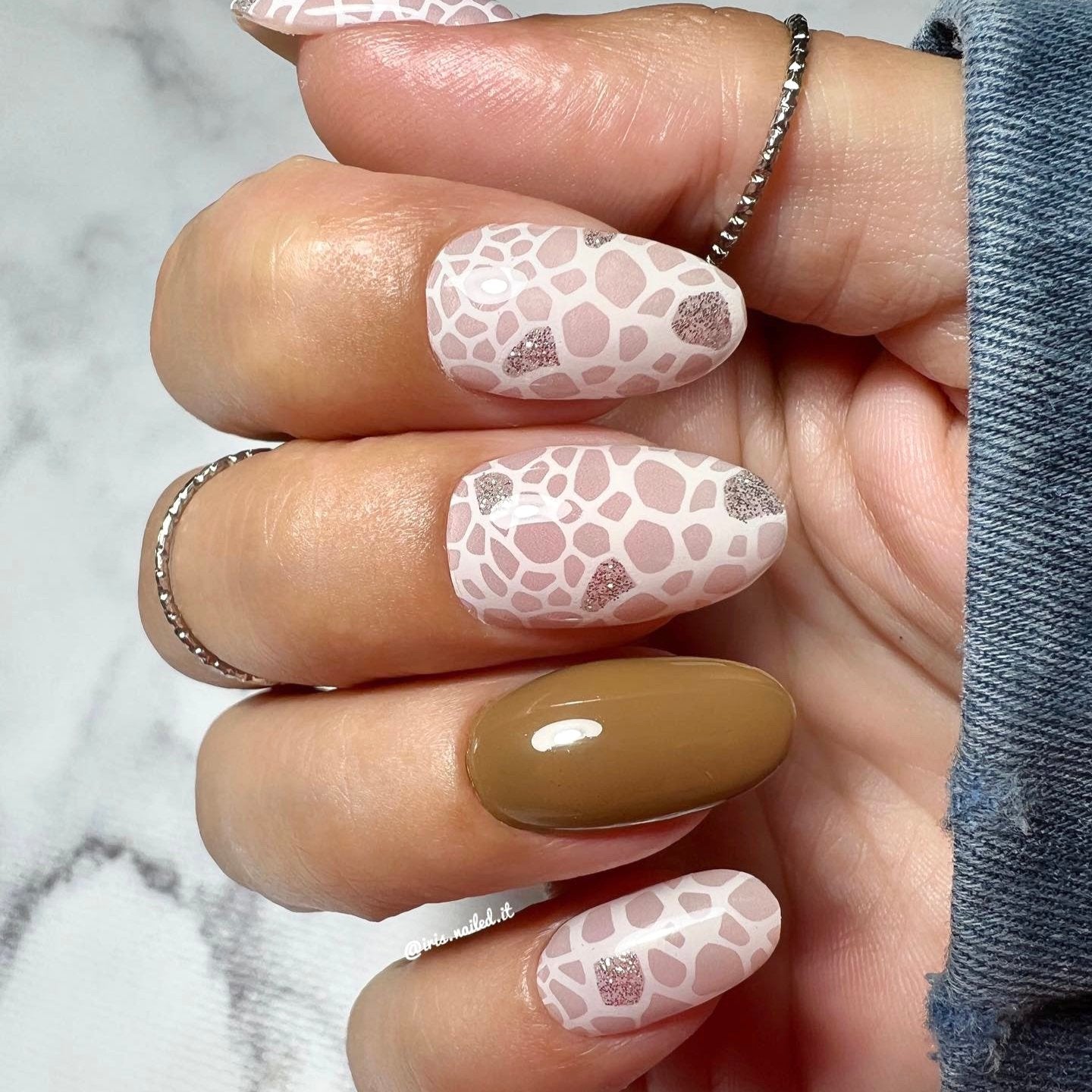 Gellakstickers met op sommige nagels effen bruin en op andere nagels witte panterprint, afgewerkt met subtiele zilveren glitter.