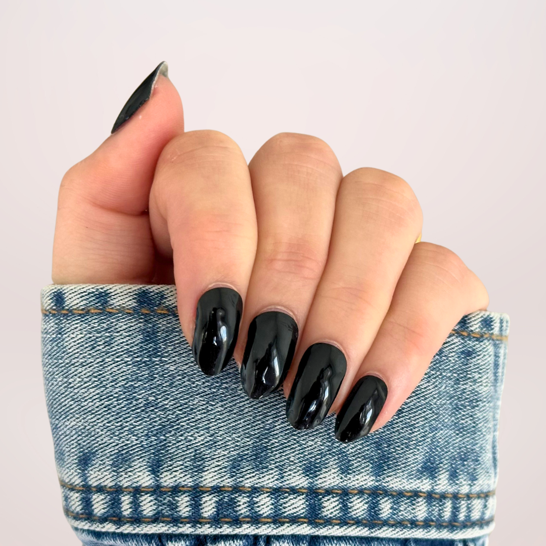 Close-up van een hand met effen zwarte gellakstickers op de nagels, die een intens diepe kleur en een strakke, glanzende afwerking tonen voor een stijlvolle en tijdloze look
