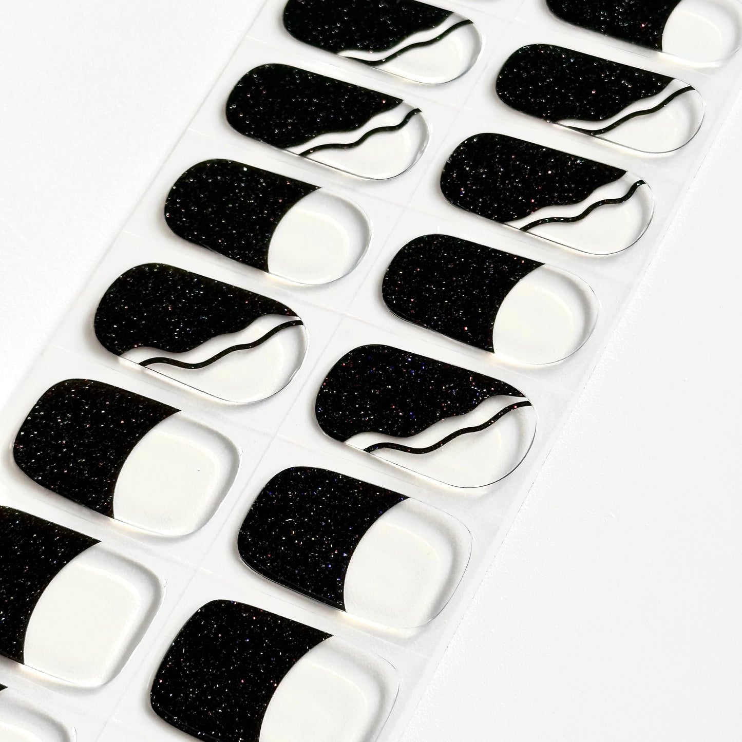 French manicure met transparante basis en zwarte diagonale tips met subtiele glitter