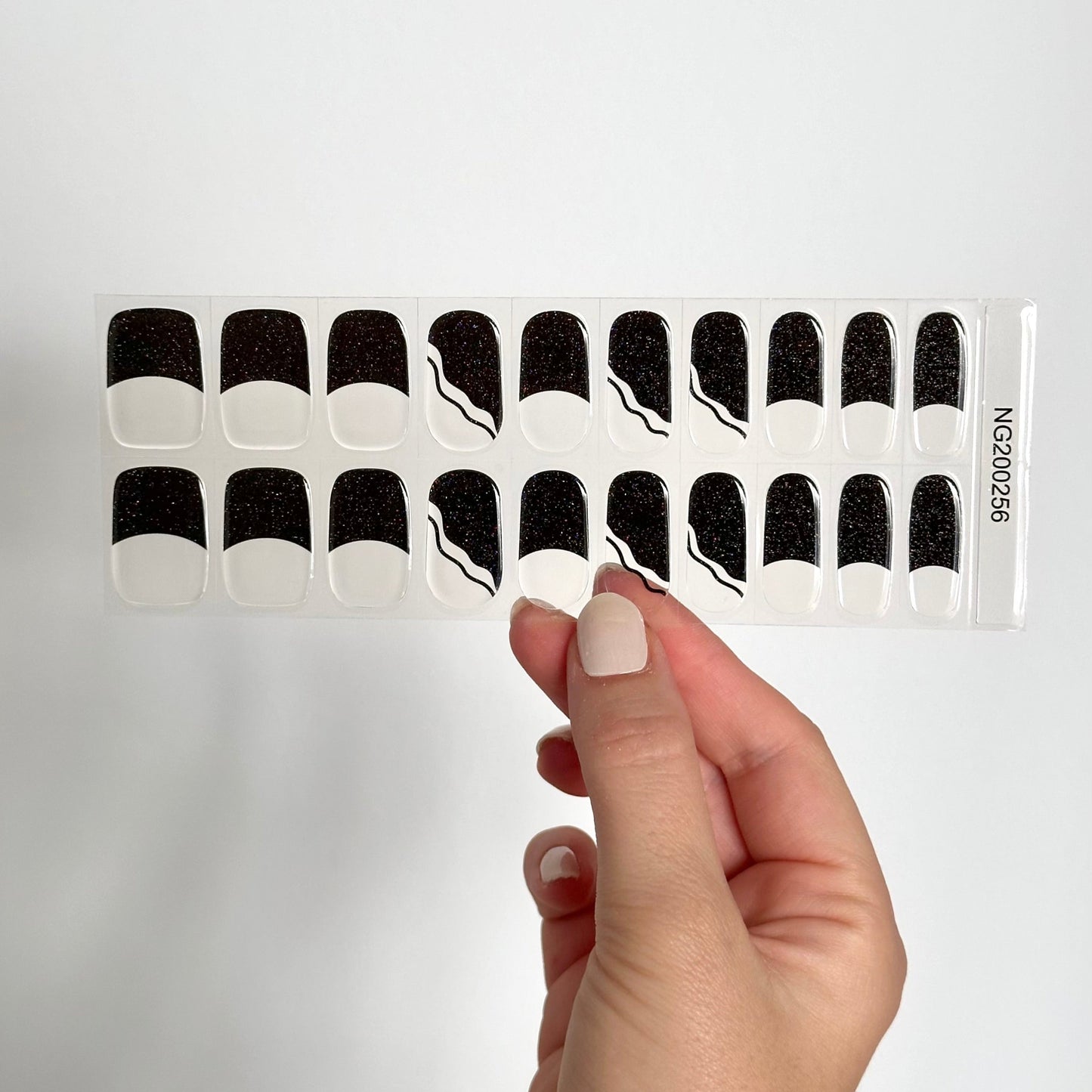 French manicure met transparante basis en zwarte diagonale tips met subtiele glitter
