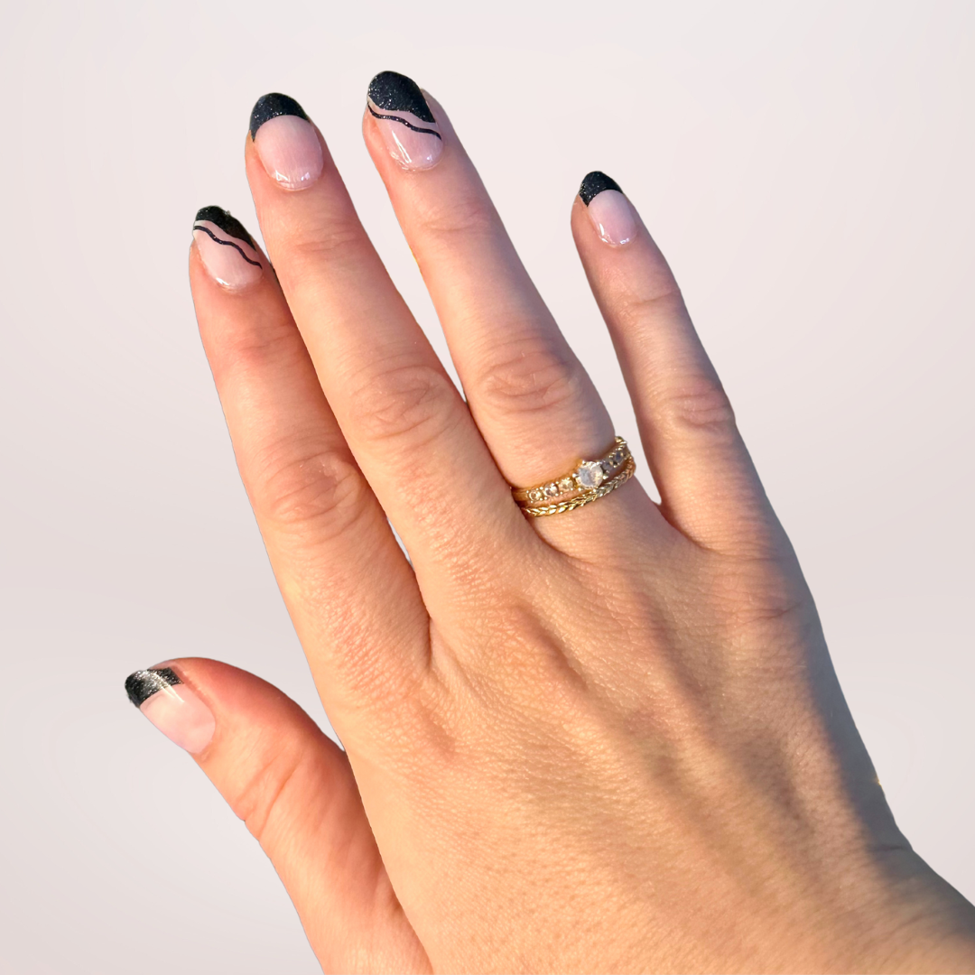 French manicure met transparante basis en zwarte diagonale tips met subtiele glitter