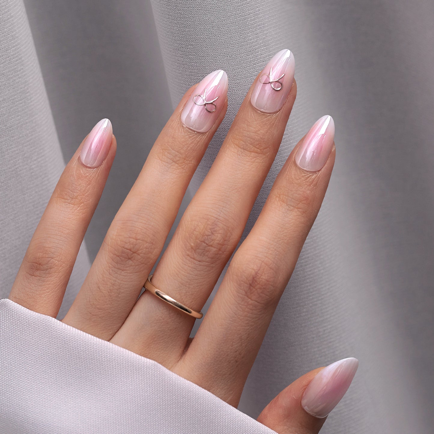 Romantische, schattige roze-witte basis met op sommige nagels een zilveren sierlijke strik als detail.