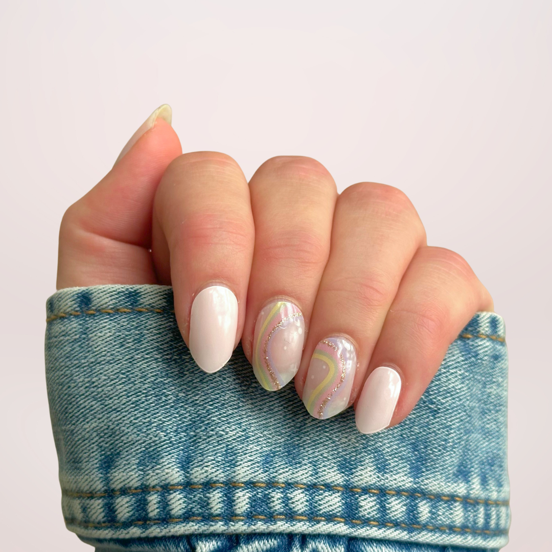 Gellakstickers met op een paar nagels effen roze en op andere nagels semi-transparante basis met zacht neutrale kleur regenboog en subtiele glitterboog