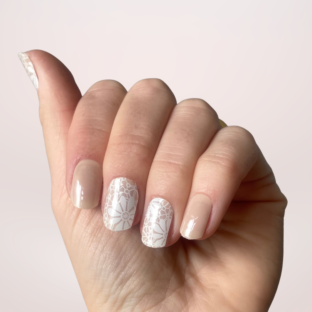 Een prachtige nude kleur met op een paar nagels nail art met witte bloemen in een 'lace' patroon.