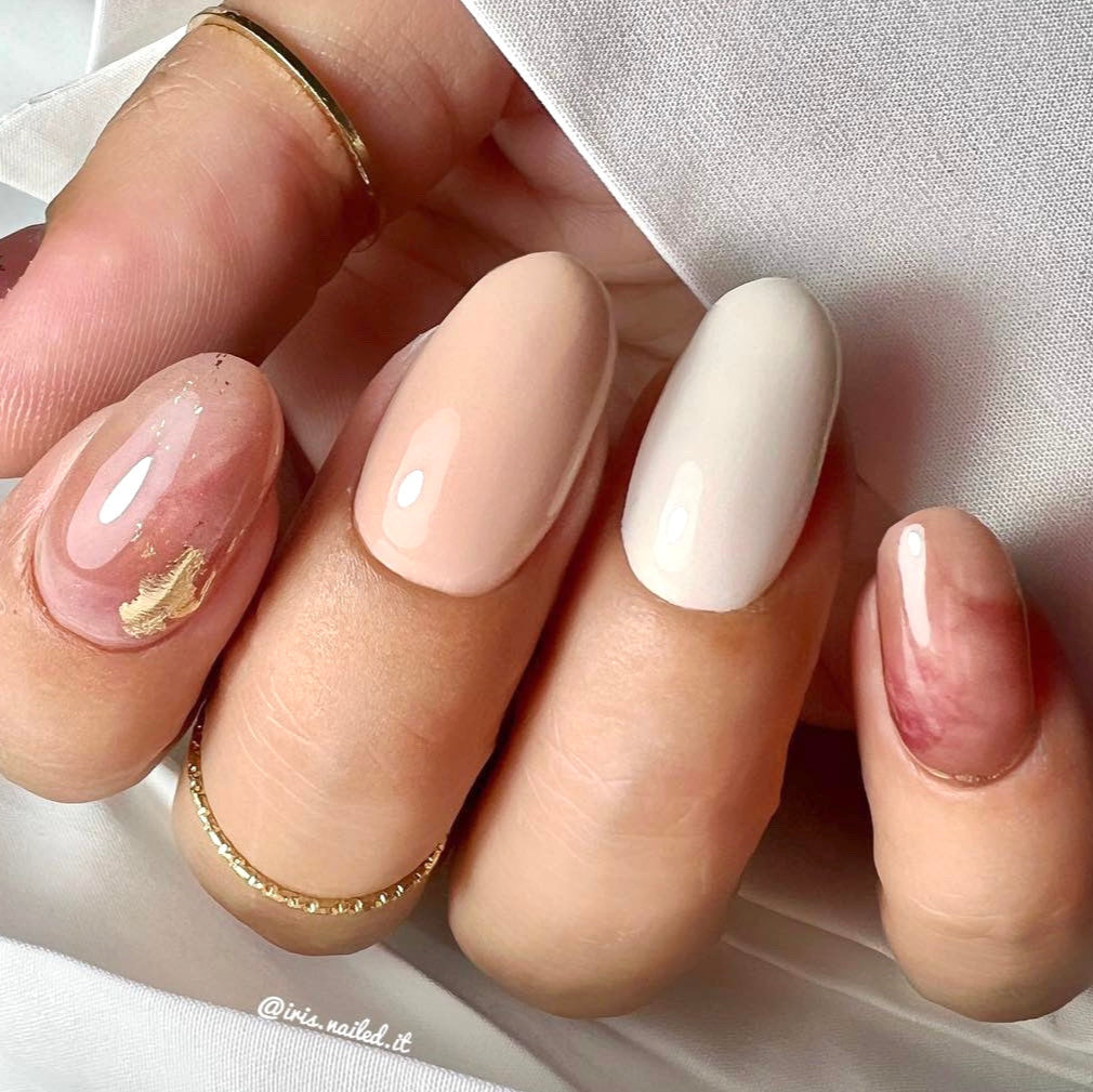 Een prachtige nail art met roze marmer en nude effen nagels met op sommige nagels gouden details