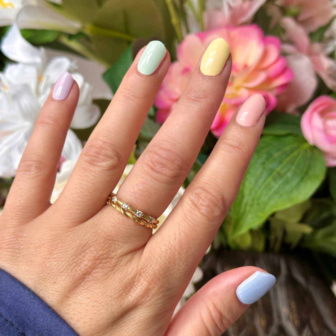Pastel Rainbow gellakstickers op de nagels met als achtergrond bloemen. Elke nagel heeft een andere pastel kleur, dit is maar net welk formaat sticker op welke nagel past.