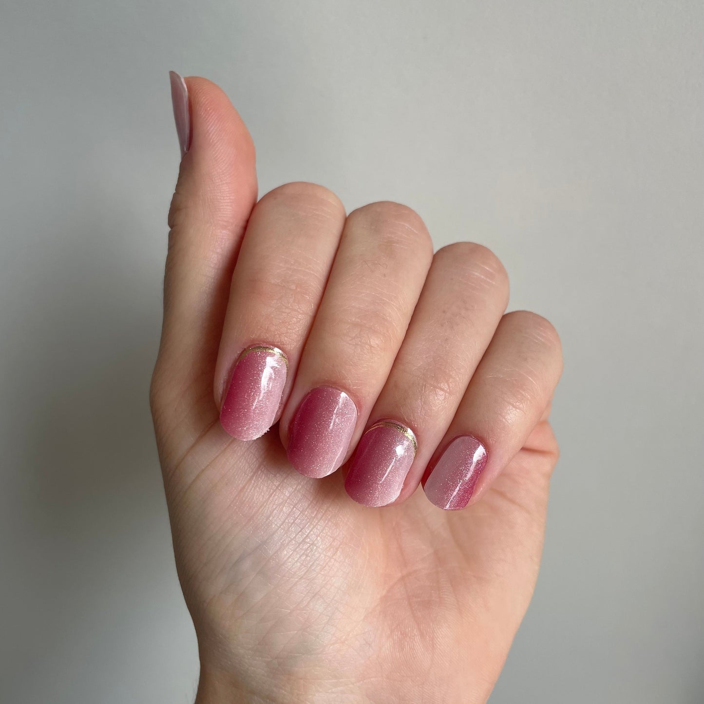 Een roze verticale ombre gellaksticker met glittertjes erdoorheen. Op sommige nagels zit aan de onderkant bij de nagelriem nog een gouden randje