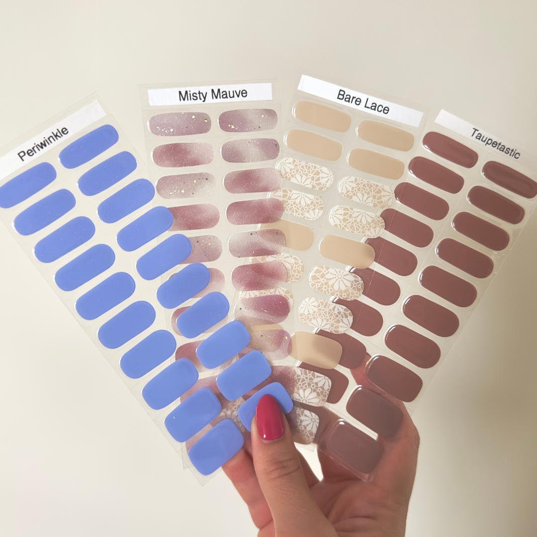 September maand bundel van 4 gellakstickers. Een paars blauwige met een subtiele shimmer, een sem transparante met soft paarse nail art, een nude design met op sommige nagels een lace effect en een taupe bruinige gellaksticker. 