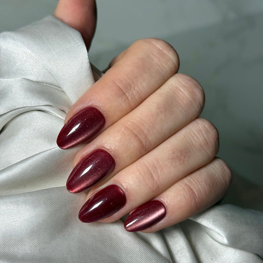 Prachtig almond vormige donkerrode nagels met een cat eye finish.