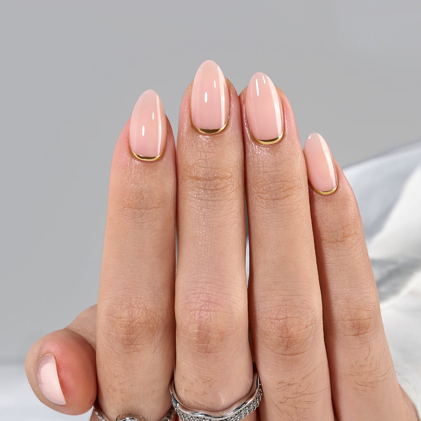 Short almond press-on nagels in een zachte roze tint met een subtiel gouden randje, genaamd 'Rosy Crown'.