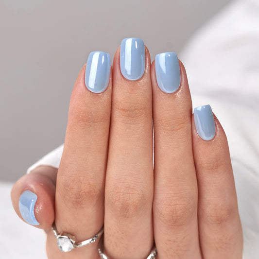 effen lichtblauwe plaknagels in een short square vorm. De nagels hebben een gladde, glanzende afwerking en stralen eenvoud en frisheid uit, perfect voor een minimalistische en zomerse look.
