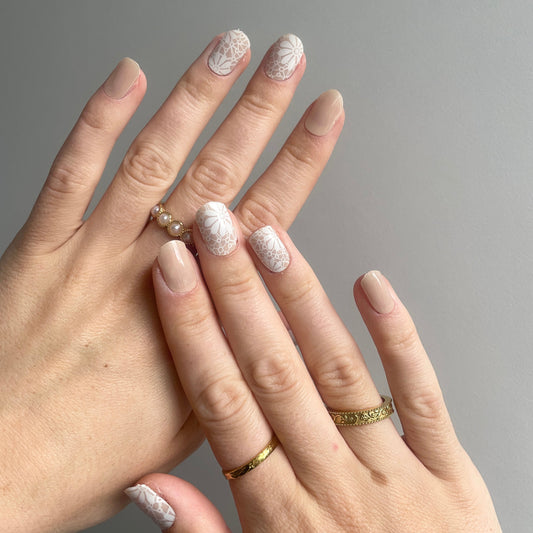 Nude kleurige gellakstickers. Sommige nagels zijn een effen nude en op een aantal nagels zit een witte bloemenprint