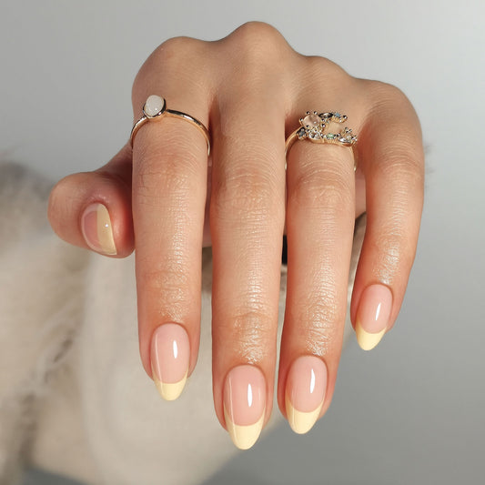 Butter yellow French press-on nagels in almond vorm met een natuurlijke nude basis en zachte botergele French tip