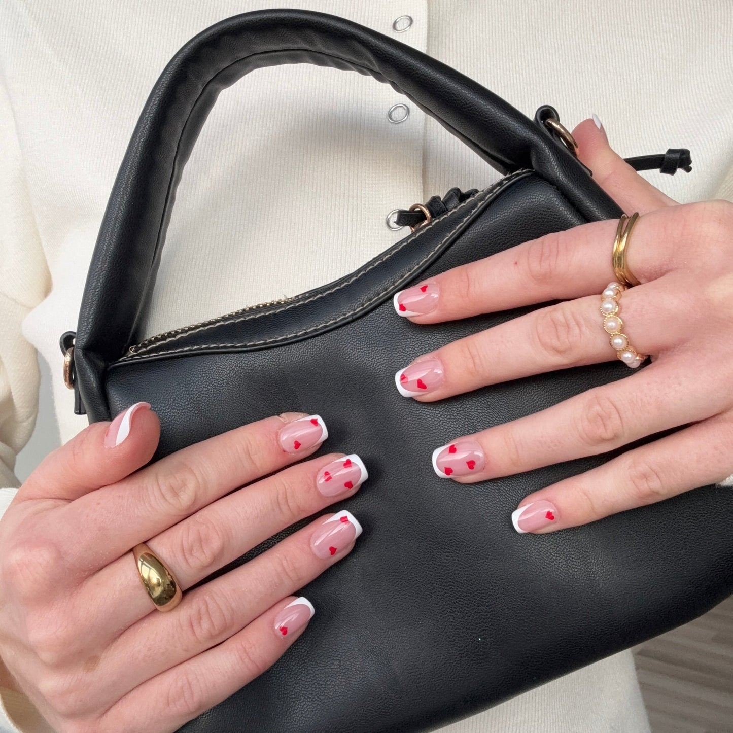 Klassieke french manicure in square vorm met subtiele rode hartjes over de press-on nagels. 