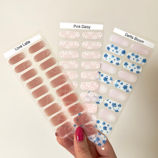 een set van 3 gellakstickers met subtiele nail arts. Delfts Bloom: een milky achtige basis met op sommige nagels blauwe bloemen. Pink Daisy: een licht roze nude basis met op alle nagels witte bloemen. Love Latte: een mooi warme roze nude/bruinige basis met een witte sierlijke swirl die in sommige nagels verloopt in een hart vorm