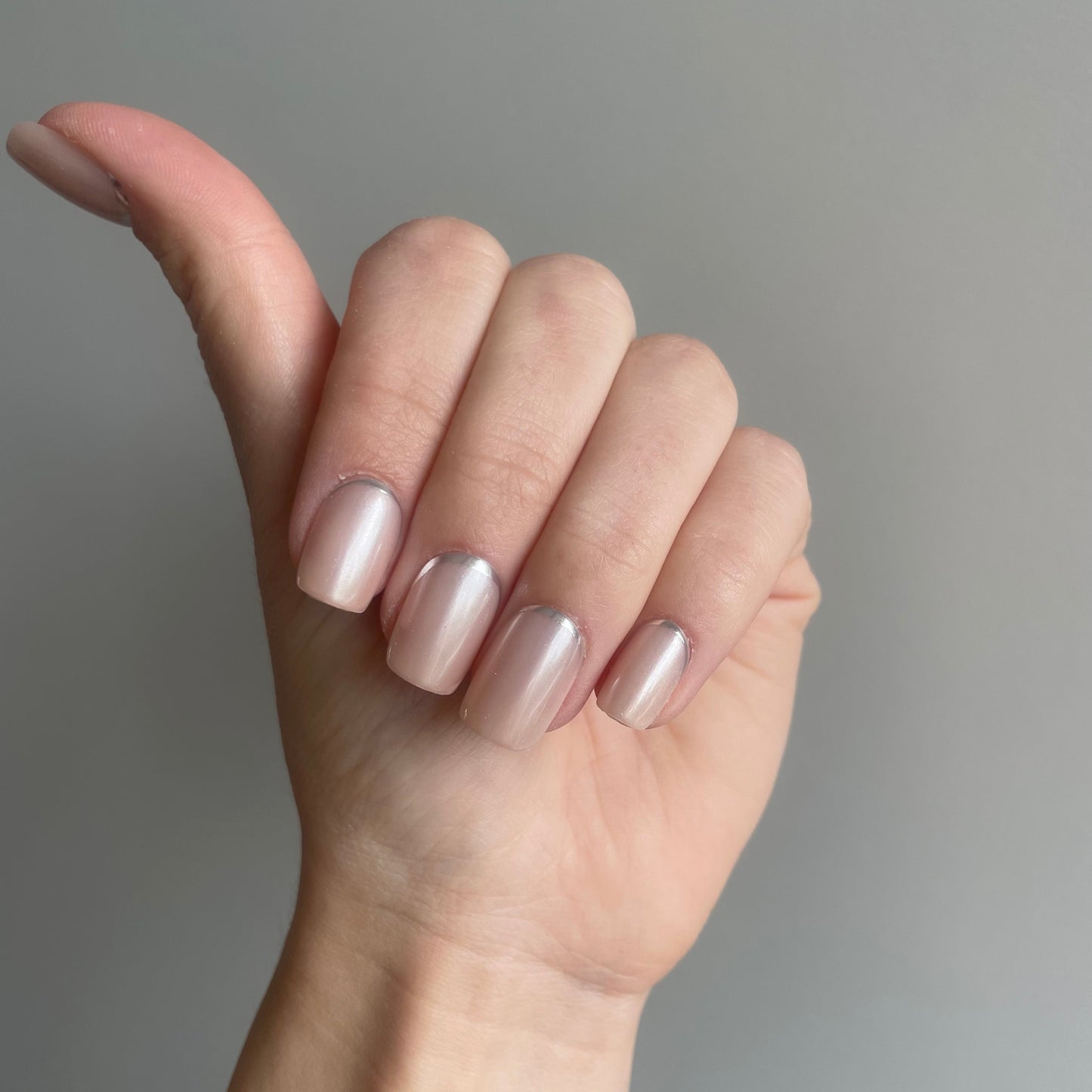short square press on nagels. Een nude kleur met subtiele shimmer en onderaan een zilveren lijn. 